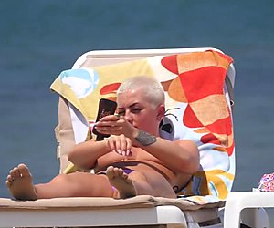 Dada besar emo pirang difilmkan di topless pantai